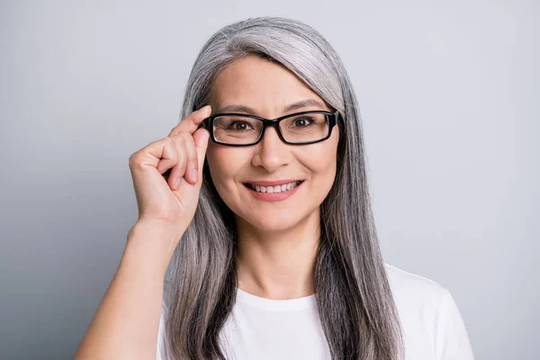 Foto de mujer jubilada sonrisa dentada look cámara mantenga especificaciones desgaste anteojos blanco camiseta aislado color gris fondo —  Fotos de Stock