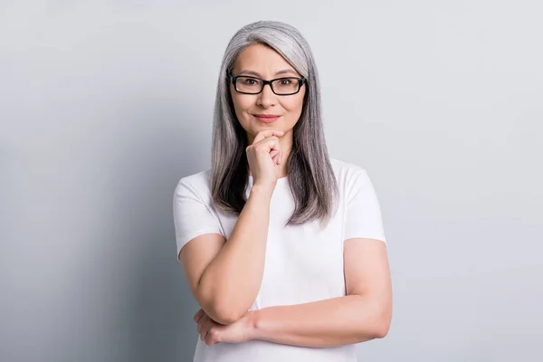 Foto di intelligente pensionato signora braccio mento sguardo fotocamera usura occhiali bianco t-shirt isolato colore grigio sfondo — Foto Stock