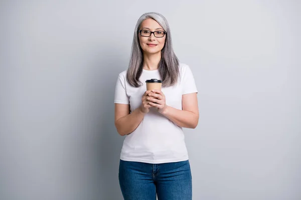 커피 토고 컵 모양의 카메라를 들고 있는 연금중인 할머니의 사진 흰색 티셔츠에 고립 된 회색 배경이 있다. — 스톡 사진