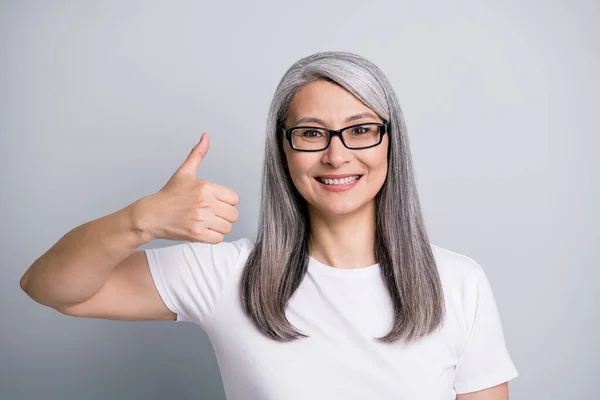 灰白头发的老年妇女的照片肖像，在灰色背景下呈手势式竖起眼镜 — 图库照片