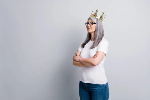 Foto van prachtige prachtige senior dame dragen casual outfit bril koningin kroon op zoek lege ruimte geïsoleerde grijze kleur achtergrond — Stockfoto