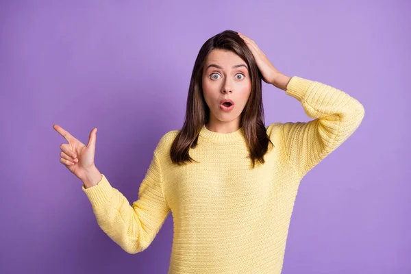Фотографія шокованої жінки, яка вказує один палець на порожній простір ізольовано на яскраво-фіолетовому фоні — стокове фото