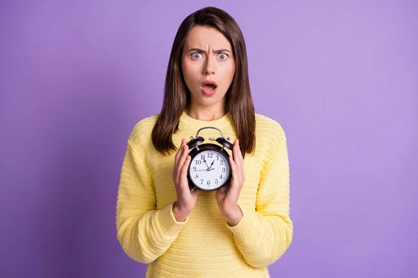 Foto retrato de mulher ansiosa perturbada segurando relógio preto em duas mãos com a boca aberta isolada em fundo colorido violeta vívido — Fotografia de Stock