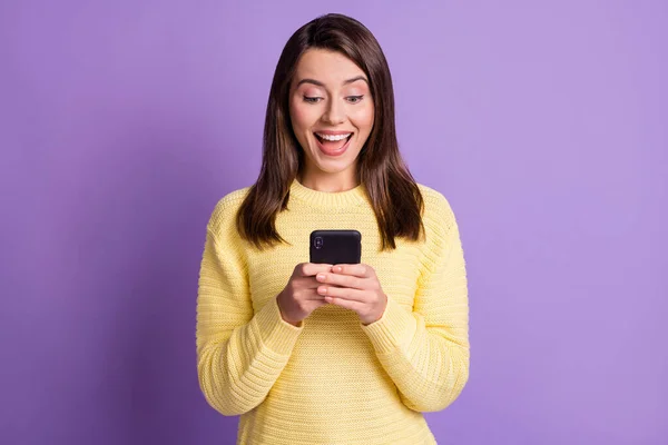 Fotoporträt von überrascht aufgeregt brünette Frau hält Telefon in zwei Händen mit offenem Mund isoliert auf lebendigen violett gefärbten Hintergrund — Stockfoto