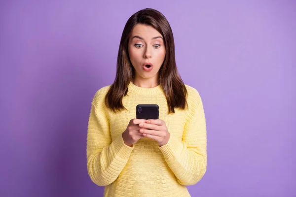 Foto portret van geschokte vrouw met mobiele telefoon in twee handen met open mond geïsoleerd op levendige violette gekleurde achtergrond — Stockfoto