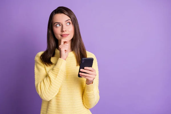 Фотопортрет жінки, яка думає тримає телефон в одній руці, торкаючись обличчя підборіддя пальцем ізольовано на яскраво-фіолетовому фоні — стокове фото