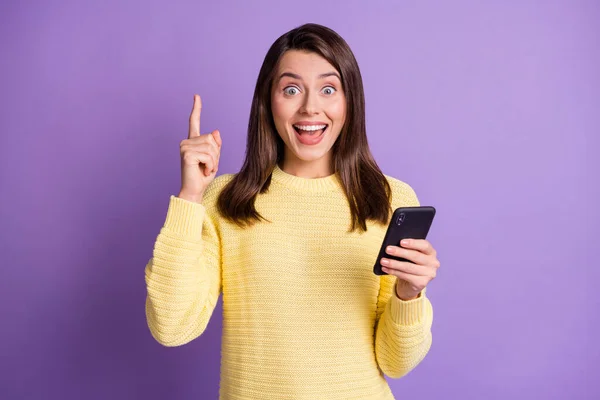 Фотографічний портрет брюнетки, яка має ясність еврики, тримає телефон в одній руці, вказуючи пальцем вгору ізольовано на яскраво-фіолетовому кольоровому фоні — стокове фото