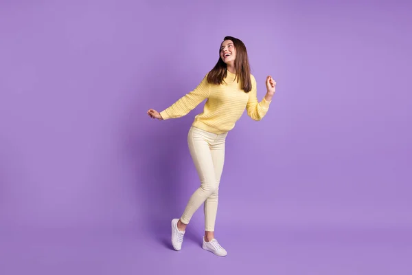 Фотопортрет повної довжини привабливої дівчини, що танцює, озираючись назад ізольовано на яскраво фіолетовому кольоровому фоні — стокове фото