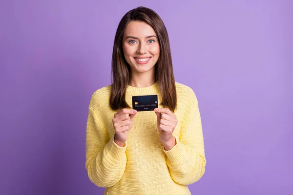 Foto de retrato de una chica morena mostrando la tarjeta de crédito del banco usando suéter amarillo casual sonriendo aislado sobre fondo de color púrpura vivo —  Fotos de Stock