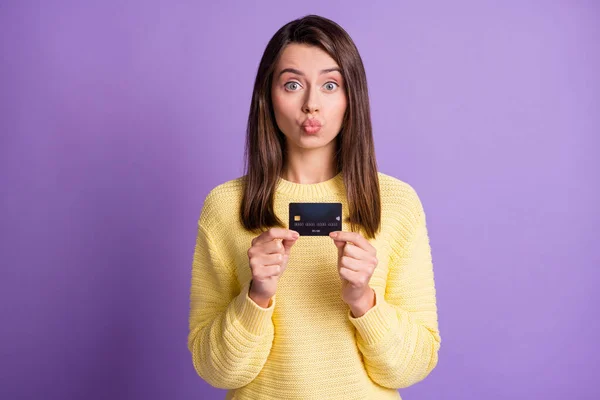 Foto retrato de novia enviando un beso de aire con labios enfurecidos mostrando la tarjeta bancaria mirando con jersey amarillo aislado sobre fondo de color púrpura vivo — Foto de Stock