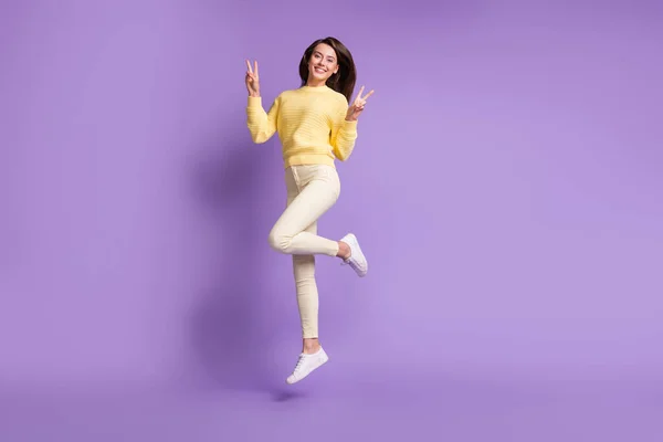 Retrato fotográfico de longitud completa de la niña saltando mostrando dos signos en V aislados sobre un fondo de color violeta vivo —  Fotos de Stock