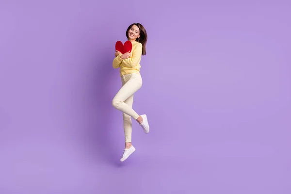 Full längd foto porträtt av flicka kramar hjärta kort hoppa upp isolerad på ljusa lila färgad bakgrund — Stockfoto