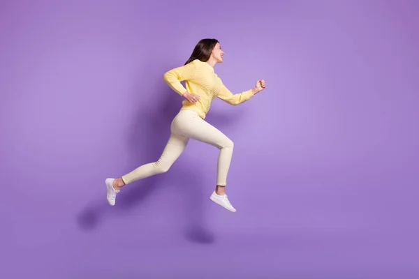 Повна довжина бокового фото портрета дівчини, що стрибає вгору ізольовано на яскравому фіолетовому кольоровому фоні — стокове фото