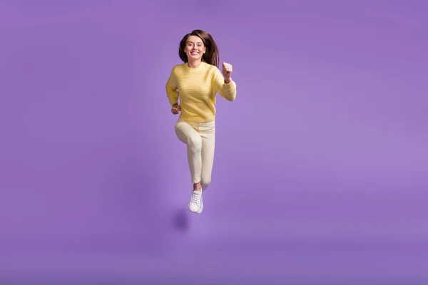 Фотографічний портрет дівчини, що стрибає вперед до камери ізольовано на яскраво-фіолетовому кольоровому фоні — стокове фото