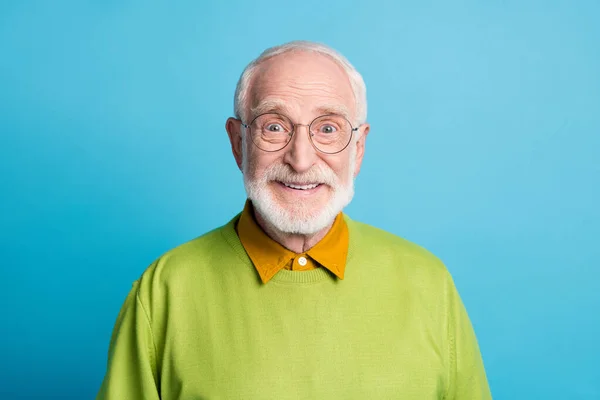 Fénykép nyugdíjas nagypapa sugárzó mosoly néz kamera kopás szemüveg zöld pulóver elszigetelt kék szín háttér — Stock Fotó