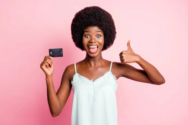 Foto de feliz mulher de cabelos castanhos mostrar polegar para cima segurar cartão de crédito comprar loja pay wear tank-top isolado no fundo cor-de-rosa — Fotografia de Stock