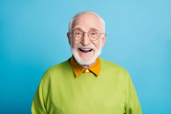 Foto de aposentado velho homem de boca aberta brilhante sorriso animado usar óculos verde pulôver isolado azul cor fundo — Fotografia de Stock