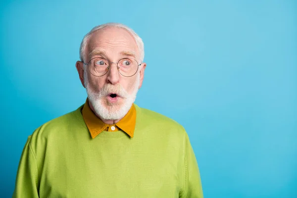 Fénykép a nyugdíjas nagypapa nyitott száj nézd oldal üres tér viselet szemüveg zöld pulóver elszigetelt kék szín háttér — Stock Fotó