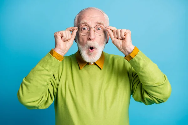 Φωτογραφία από σοκαρισμένος συνταξιούχος παππούς όπλα κατέχουν specs φορούν γυαλιά πράσινο πουλόβερ απομονωμένο μπλε χρώμα φόντο — Φωτογραφία Αρχείου
