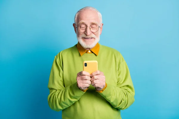 引退した老人の写真を保持電話の外観画面を着用眼鏡緑のプルオーバー隔離された青の色の背景 — ストック写真