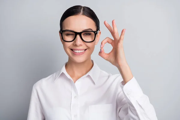 Foto de flerte coquete conselheiro piscar de olhos mostrar óculos okey desgaste camisa branca isolado fundo cor cinza — Fotografia de Stock