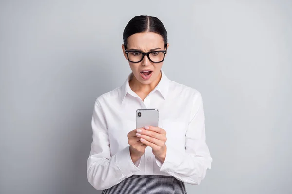 Φωτογραφία του άφωνος επιχειρηματίας κυρία κρατήσει smartphone ανοιχτό στόμα κοιτάζοντας φορούν γυαλιά λευκό πουκάμισο απομονωμένο γκρι χρώμα φόντο — Φωτογραφία Αρχείου