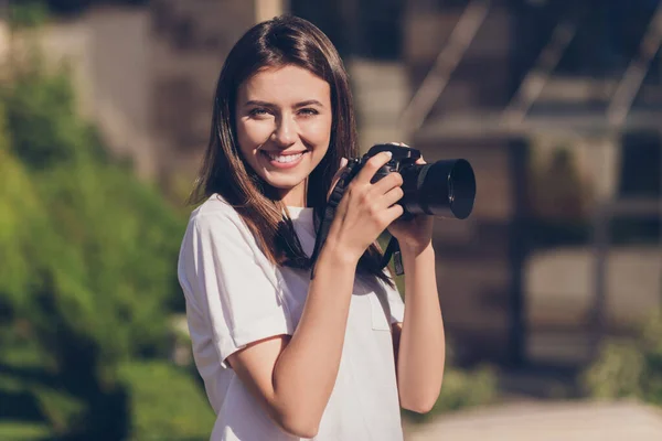 Foto retrato de una mujer sosteniendo una cámara digital sonriendo al aire libre —  Fotos de Stock