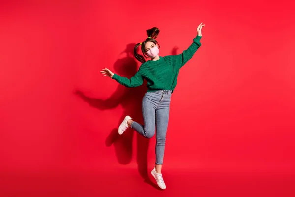 Foto de mulher feliz atraente saltar ar levantar mãos usar máscara de proteção jeans isolado no fundo de cor vermelha — Fotografia de Stock