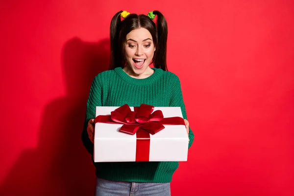 Photo of young beautiful shocked surprised smiling female receive gift present isolated on red color background — Stock Photo, Image