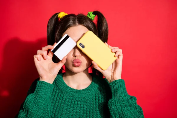 Portrait of young attractive lovely charming girl pout lips cover eyes with credit card phone isolated on red color background — Stock Photo, Image