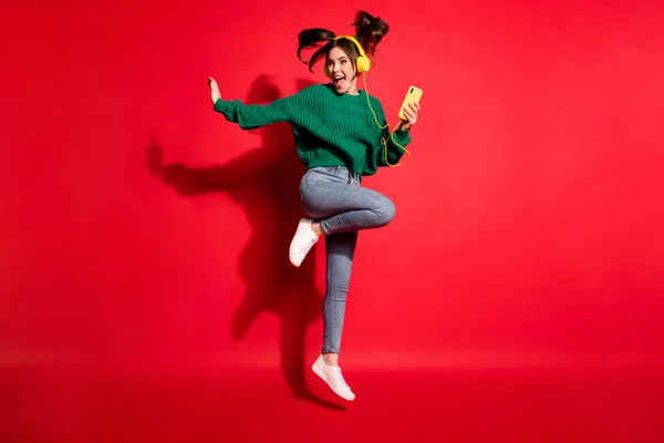 Yeşil örülü süveter giyen, dans eden, izole edilmiş kırmızı arka planda dans eden hoş bir genç kadının tam boy fotoğrafı. — Stok fotoğraf