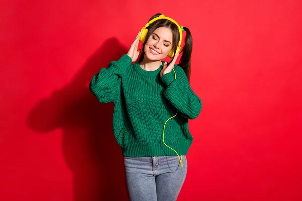 Φωτογραφία από γοητευτικό αξιολάτρευτο νεαρή γυναίκα ντυμένος πράσινο πλεκτό πουλόβερ βραχίονες ακουστικά απομονωμένο κόκκινο χρώμα φόντο — Φωτογραφία Αρχείου