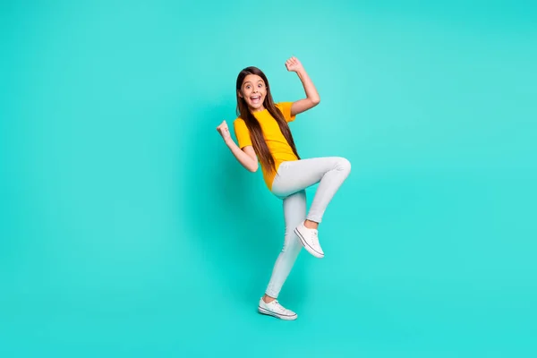 Foto de longitud completa de niña loca levantar los puños de pie aislado sobre fondo de color verde azulado —  Fotos de Stock