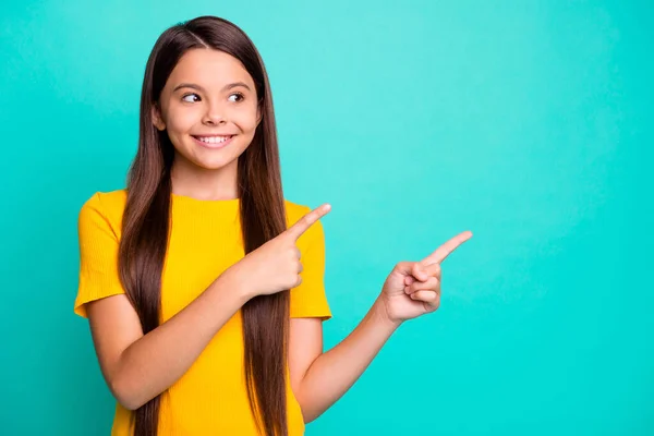 Positivo niña punta dedo índice espacio vacío para los anuncios de promoción usan ropa amarilla aislada sobre fondo de color turquesa — Foto de Stock