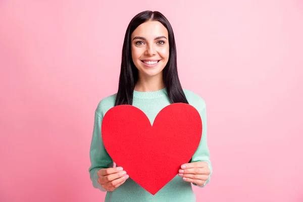 Foto retrato de jovem namorada mantendo vermelho papel coração postcarg sorrindo no dia dos namorados isolado no fundo cor-de-rosa pastel — Fotografia de Stock