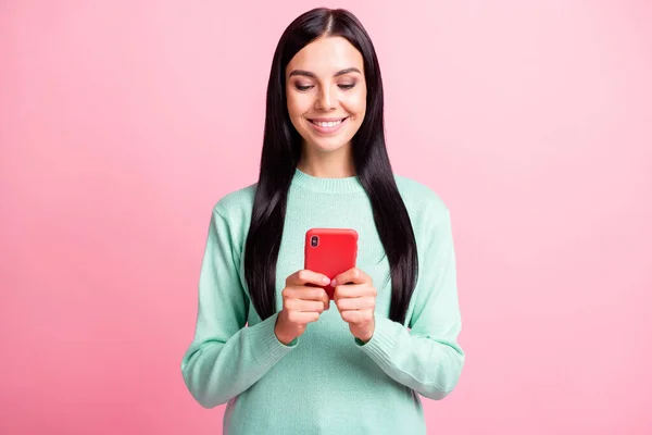 Foto retrato de una mujer sosteniendo el teléfono con dos manos escribiendo aislado sobre fondo de color rosa pastel — Foto de Stock