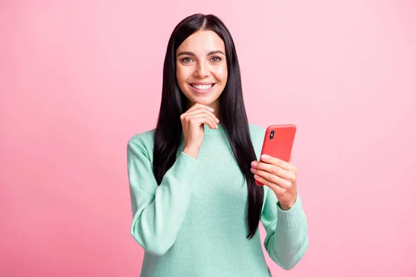 Foto portret van de planning vrouw aanraken gezicht kin holding telefoon in een hand geïsoleerd op pastel roze gekleurde achtergrond — Stockfoto