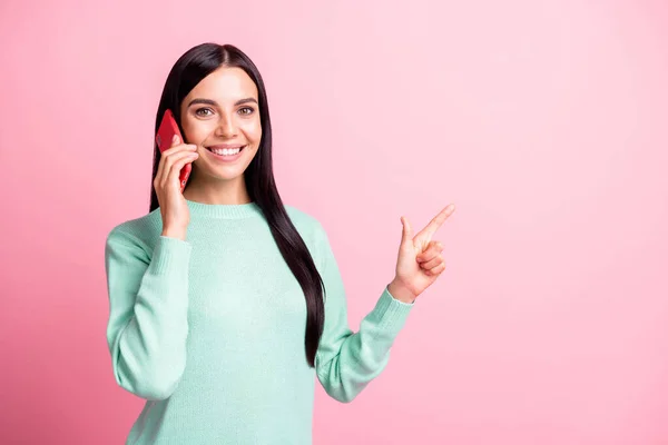 Foto retrato de menina falando no telefone apontando o dedo para o espaço em branco isolado no fundo de cor rosa pastel — Fotografia de Stock