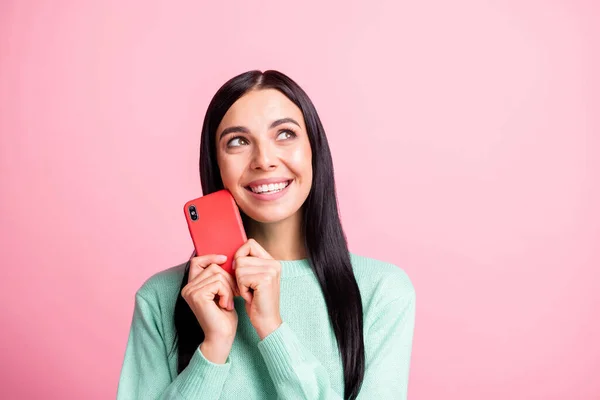Фотопортрет мрійливої жінки, що тримає телефон біля обличчя ізольовано на пастельному рожевому фоні — стокове фото