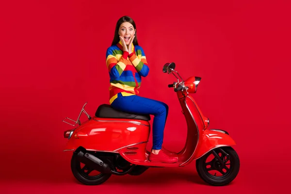 Retrato de encantador alegre menina surpreso sentado na ciclomotor ter divertido grande venda isolado sobre fundo de cor vermelha brilhante — Fotografia de Stock