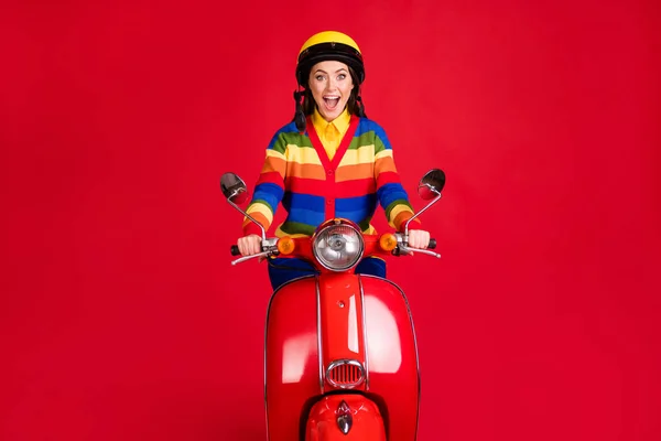 Фотографічний портрет кричущої жінки, що катається на скутері ізольовано на яскраво-червоному тлі — стокове фото