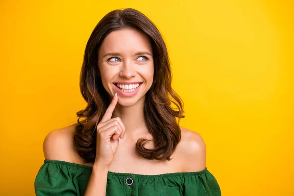 Фото щасливої мрійливої молодої жінки, яка тримає палець підборіддя посмішка виглядає порожнім простором ізольовано на жовтому тлі — стокове фото