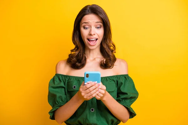 照片中迷人迷人的年轻漂亮的女士手持智能手机，用黄色背景隔离出令人惊讶的信息 — 图库照片