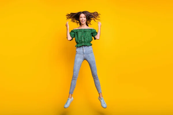 Lunghezza completa foto di gioiosa dolce giovane donna volare capelli alzare le mani saltare aria isolata su sfondo di colore giallo brillante — Foto Stock