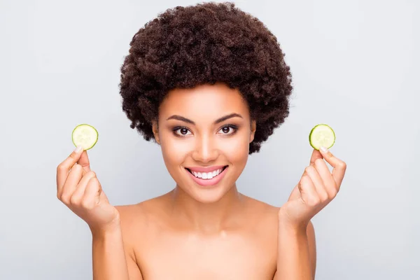 Retrato de cerca de agradable atractiva chica alegre de pelo ondulado sosteniendo en la mano piezas de pepino anti terapia de edad tratamiento rejuvenecimiento perfección aislado sobre fondo pastel de color gris claro — Foto de Stock