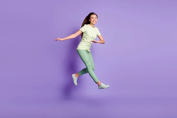 Retrato de longitud completa de salto de dama atractiva divertirse sonrisa dentada usar ropa verde aislado sobre fondo de color púrpura — Foto de Stock