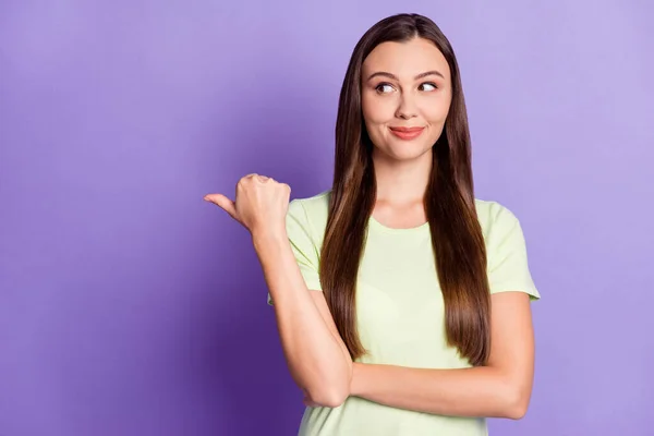 Portrait of satisfied woman look indicate finger empty space light green t-shirt isolated on purple color background — 图库照片