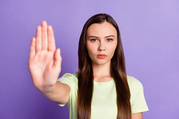 Retrato de una persona seria mostrar el brazo señal de parada de la palma usando ropa verde claro aislado en el fondo de color púrpura —  Fotos de Stock