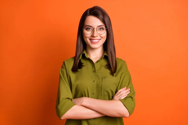 Foto porträtt av kvinnliga frilansare ler med vikta händer bär glasögon grön skjorta isolerad på ljusa orange färg bakgrund — Stockfoto