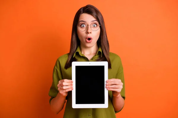 Portrait photo d'une étudiante stupéfaite tenant une tablette montrant un espace de copie à écran tactile isolé sur un fond de couleur orange vif — Photo